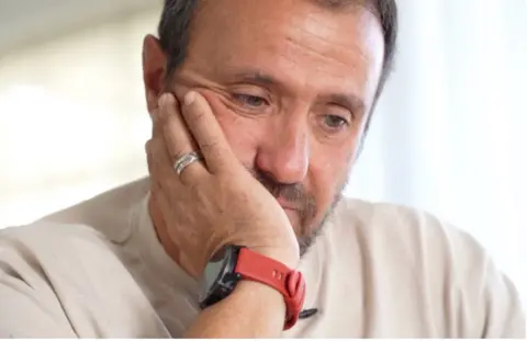 Avi Harush, father of killed soldier Reef, rests his chin on his hand