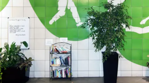 Oval Underground station interior features potted plants, book exchange, Thought of the Day