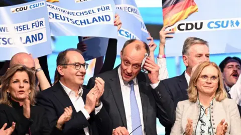 Reuters Friedrich Merz wipes as he is joined by party colleagues in a Munich beer hall for a final rally