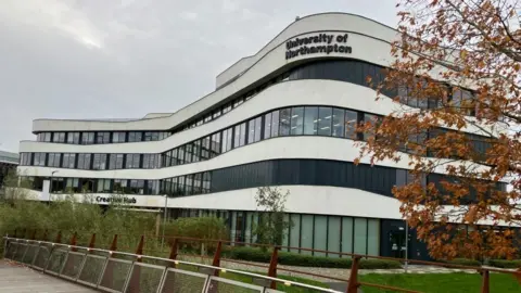 James Grant/BBC A four-storey modern white curved building with "University of Northampton" sign on the top.