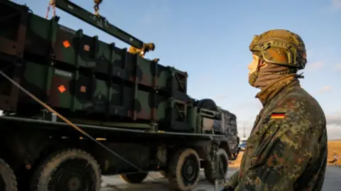 A German soldier stands beside a military truck