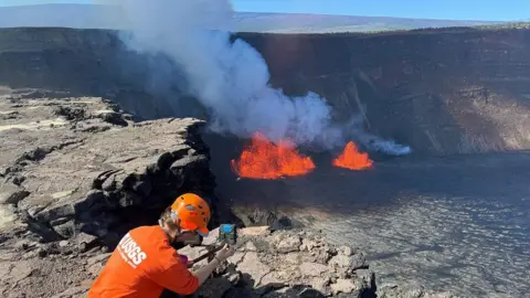 USGS A U.S. Geological Survey Hawaiian Volcano Observatory geologist checks a webcam located on the rim of the caldera