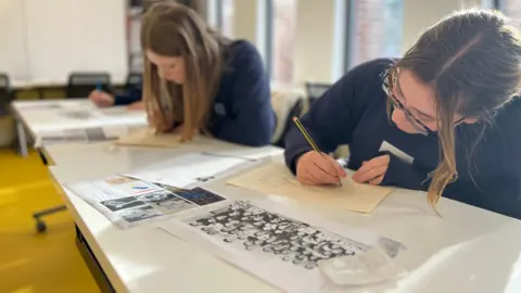 Two school students drawing at a desk, along with a black and white class photograph.