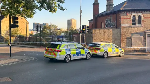 Alice Cunningham/BBC An officer and two police cars at the cordon in Ipswich
