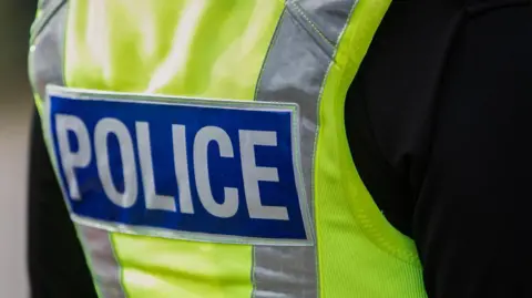 A close up of a police officer wearing a high visibility vest.