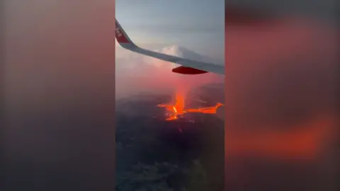 A view from an EasyJet plane window as it flies above and to the side of an erupting volcano