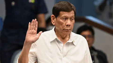 Getty Images Rodrigo Duterte takes an oath as he attends a senate probe on the drug war during his administration, in Manila on 28 October 2024.