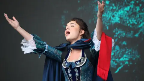 Alamy Holly-Anne Hull in costume in Les Miserables, singing, with her arms outstretched