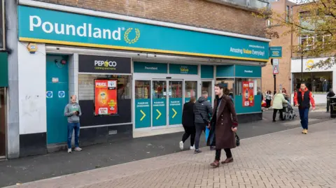 Getty Images A Poundland store with people walking past on a paved street