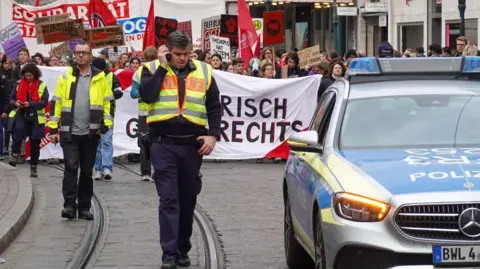 Getty Images Demonstrators march on a street escorted by German police 