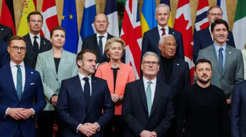 Reuters Sir Keir Starmer, Emmanuel Macron and Volodymyr Zelensky surrounded by other world leaders in a group photo in front of their nation's flags at Lancaster House.