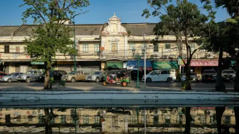 An image of a street in Bangkok, Thailand, with tuk-tuks visible