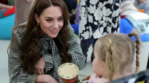 PA The Princess of Wales smiling with a small white girl with blonde hair and pigtails