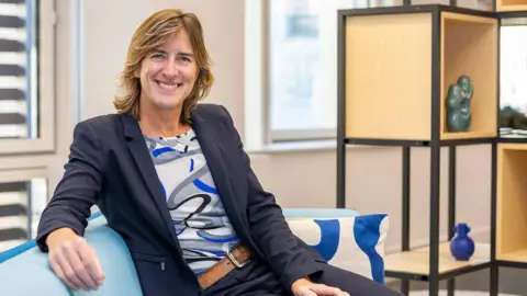 Team GB Dame Katherine Grainger smiles at the camera while sitting on a sofa