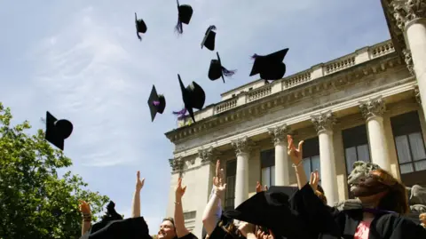 New graduates throw their mortarboard hats into the air following their graduation ceremony at Portsmouth's Guildhall